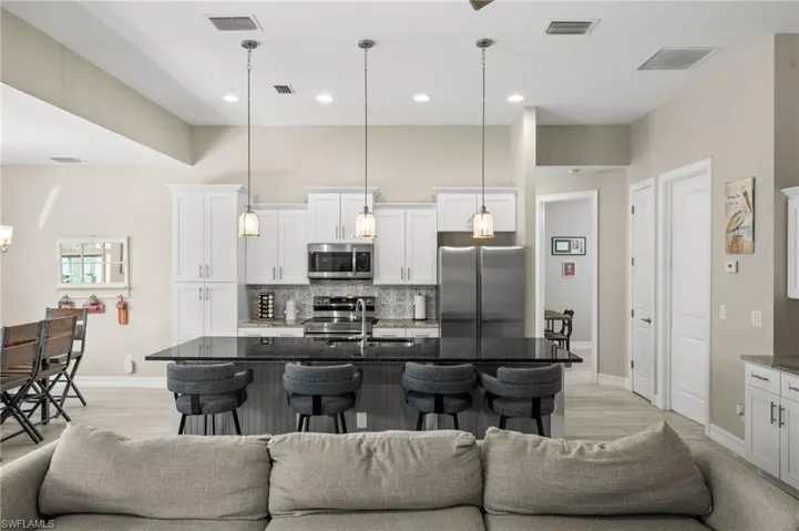 Kitchen with open floor plan, dark stone countertops, a kitchen breakfast bar, appliances with stainless steel finishes, and a high ceiling