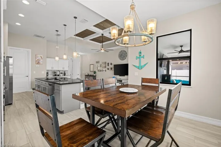 Dining room featuring a chandelier, coffered ceiling, a ceiling fan, beamed ceiling, and recessed lighting