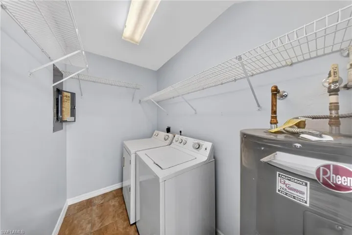 Laundry area featuring wire shelving, a water heater, and wood-finish flooring