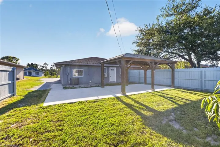 Spacious backyard featuring a wood-frame pergola over a concrete patio, a manicured lawn, and privacy fencing