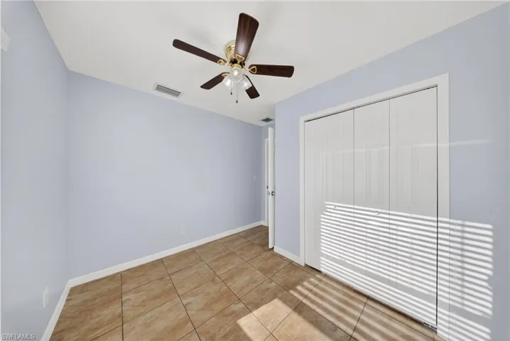 Room featuring ceramic tile flooring, a ceiling fan with integrated lighting, bi-fold closet doors, and light blue wall tones