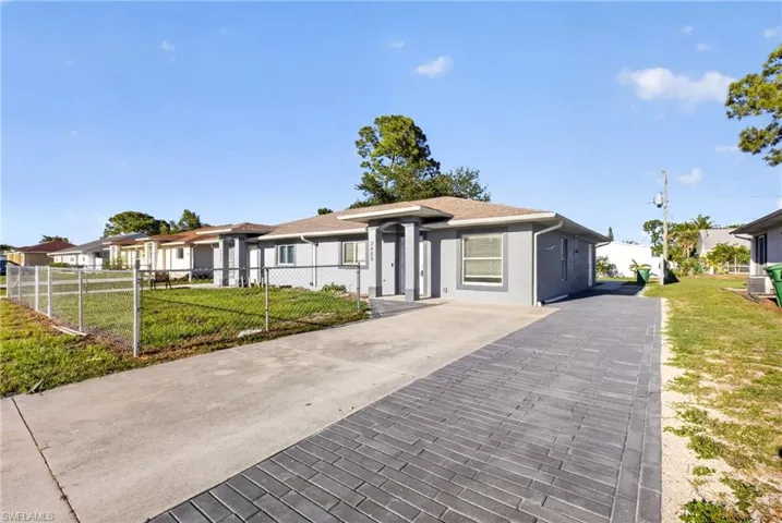 Contemporary stucco exterior featuring a flat roofline and a dark paver driveway