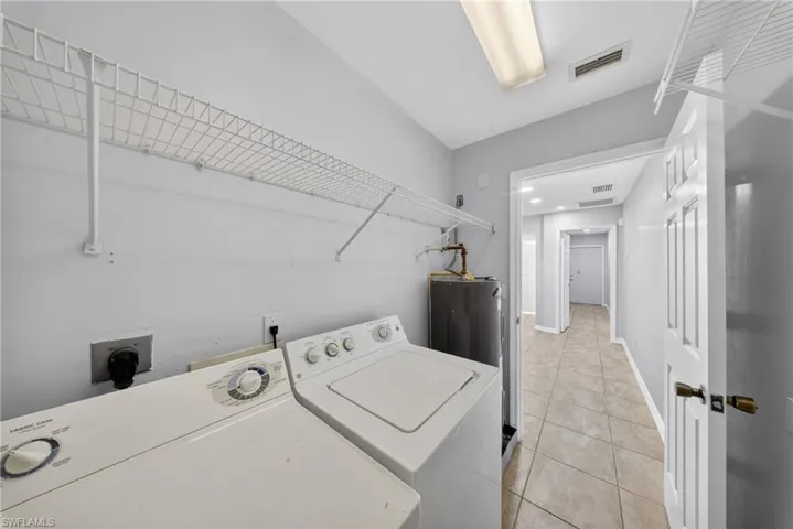Dedicated utility space featuring a water heater, white wire shelving, and tiled flooring