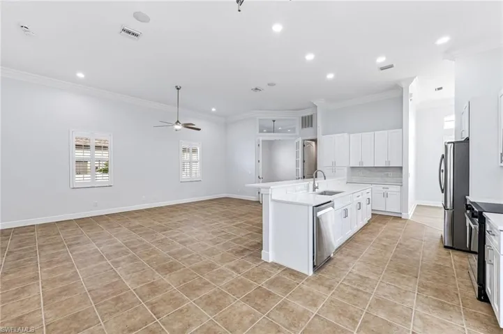 Kitchen featuring ceiling fan, sink, a kitchen island with sink, white cabinetry, and appliances with stainless steel finishes