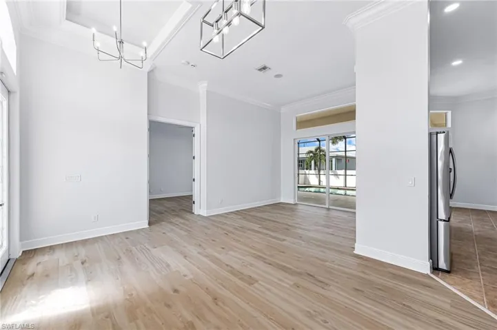 Unfurnished room featuring light wood-type flooring, ornamental molding, and a notable chandelier