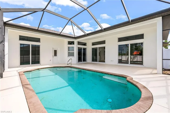 View of pool with glass enclosure and a patio area