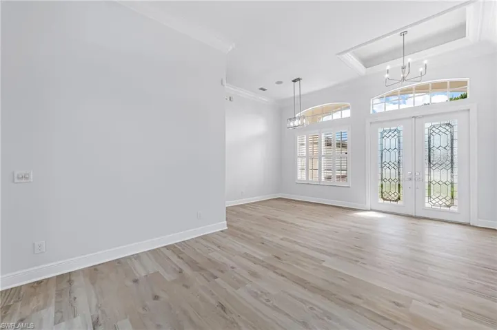 Foyer featuring french doors, an inviting chandelier, light wood-type flooring, and ornamental molding