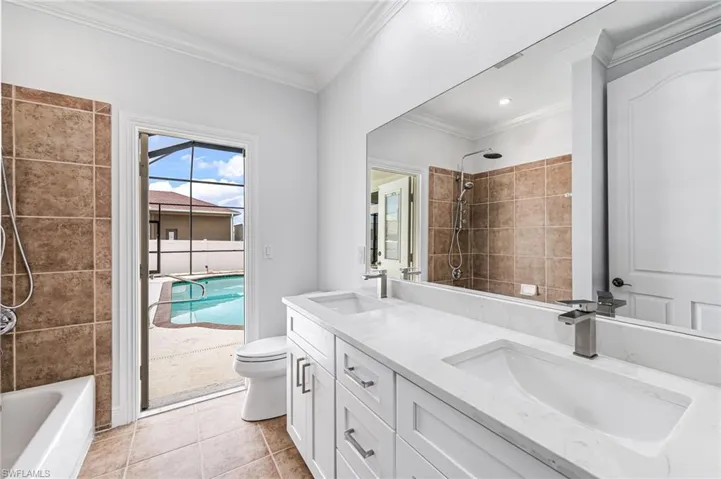 Full bathroom featuring tile patterned flooring, ornamental molding, vanity, tiled shower / bath, and toilet