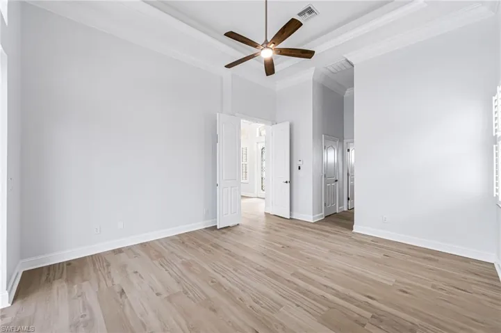 Unfurnished bedroom with light wood-type flooring, ceiling fan, a high ceiling, and crown molding