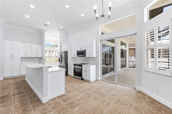 Kitchen with pendant lighting, appliances with stainless steel finishes, backsplash, and white cabinets