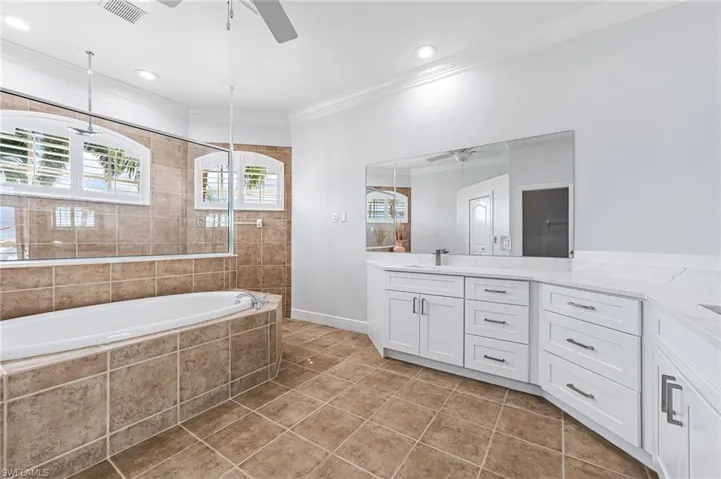 Bathroom with vanity, crown molding, ceiling fan, plus walk in shower, and tile patterned floors