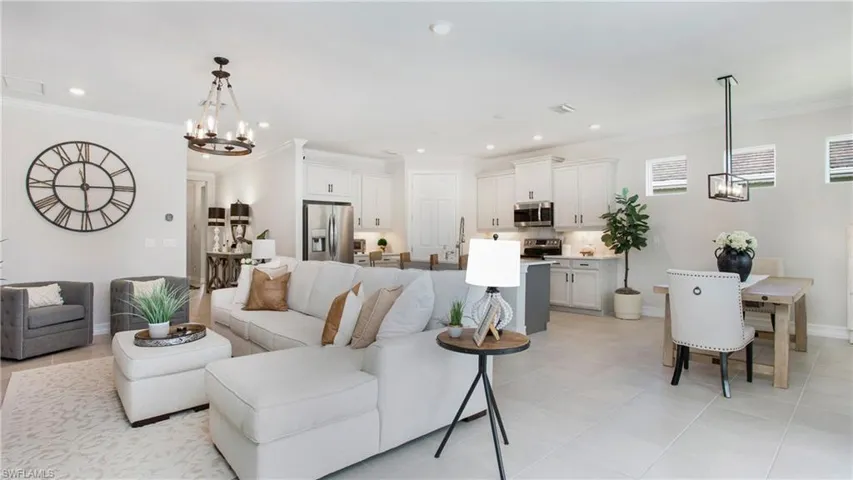 Living room with ornamental molding, light tile patterned flooring, and a notable chandelier