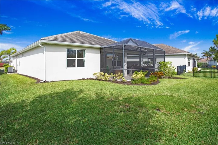 Rear view of house featuring a lanai and a lawn