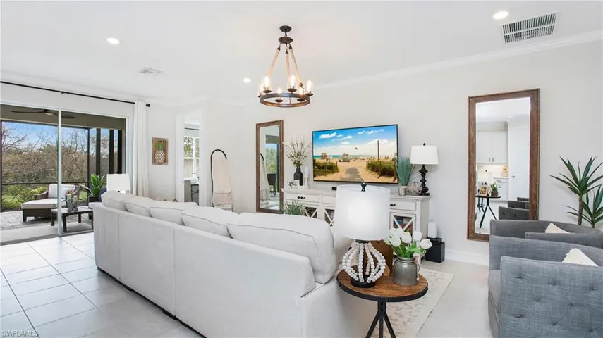 Living room featuring a notable chandelier, ornamental molding, and light tile patterned floors