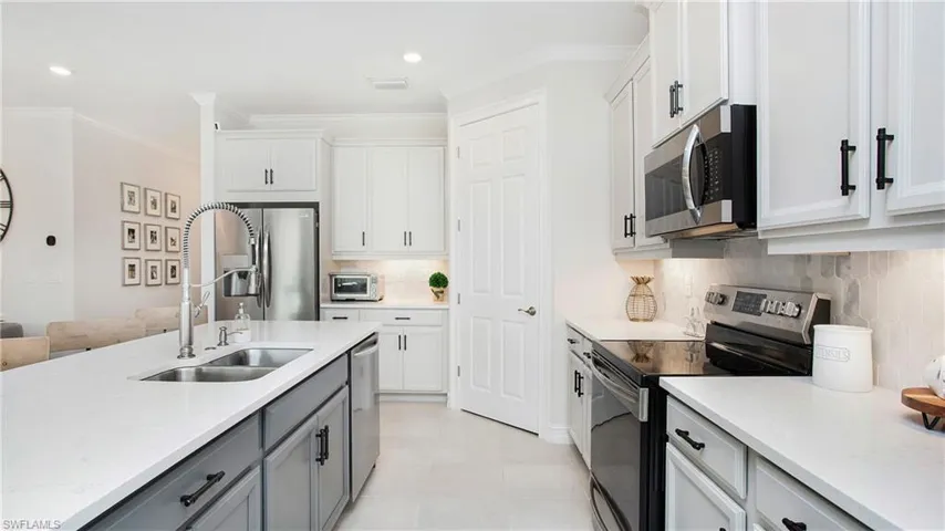 Kitchen featuring decorative backsplash, white cabinets, stainless steel appliances, and sink