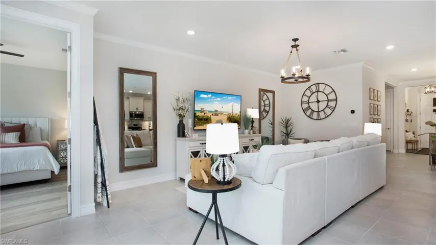 Tiled living room featuring ornamental molding and a chandelier