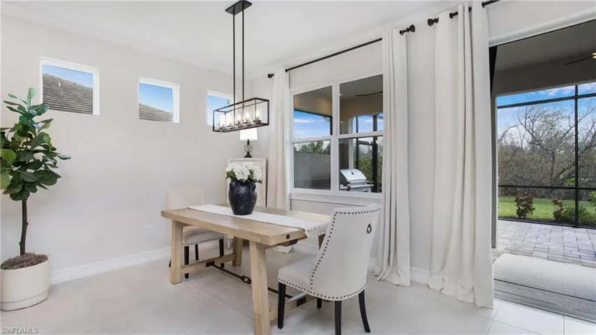 Tiled dining space featuring an inviting chandelier, crown molding, and a healthy amount of sunlight