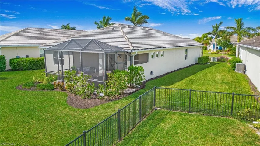 Back of property with a yard, central AC unit, and a lanai