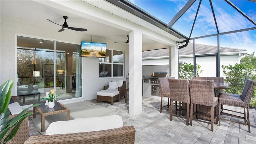 View of patio with ceiling fan, a lanai, grilling area, and exterior kitchen