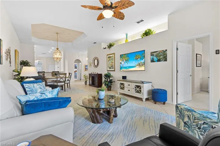 Tiled living room featuring ceiling fan with notable chandelier