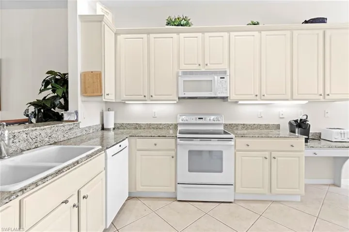 Kitchen with sink, white cabinets, white appliances, and light tile floors