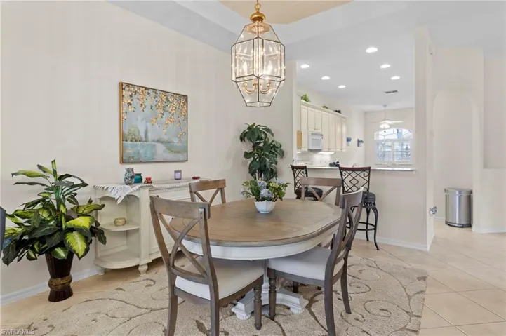 Dining area featuring light tile floors and ceiling fan with notable chandelier