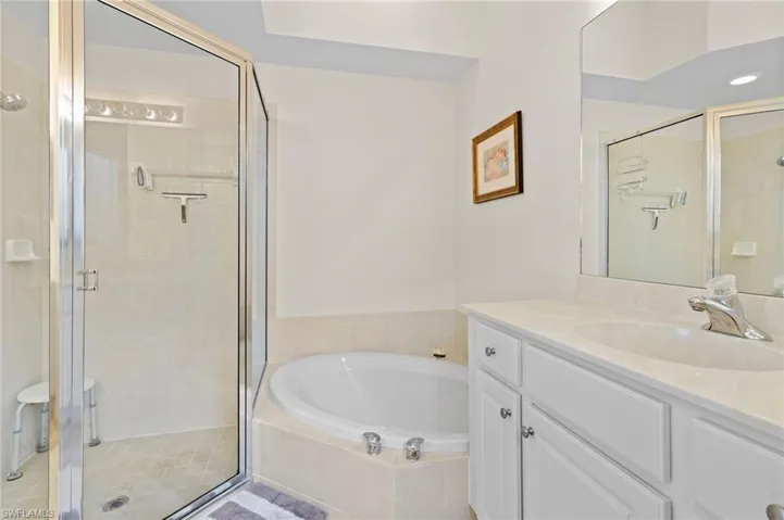Bathroom with tile flooring, separate shower and tub, and vanity with extensive cabinet space