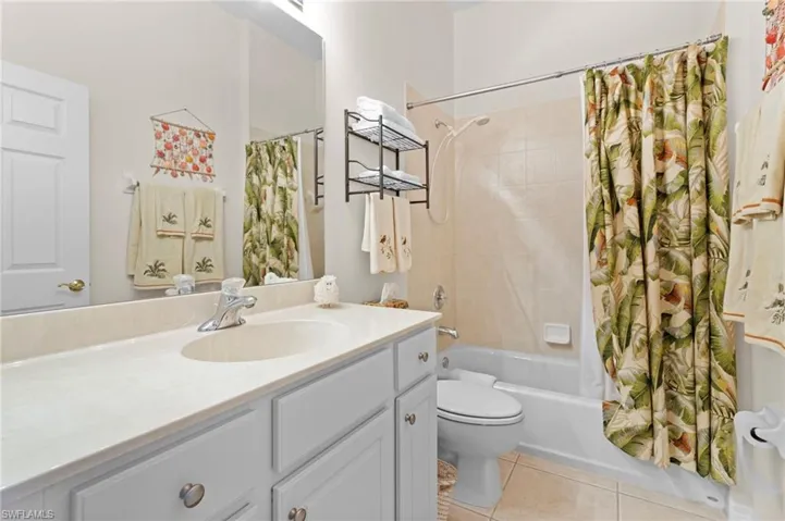 Full bathroom with tile floors, shower / tub combo with curtain, toilet, and vanity with extensive cabinet space