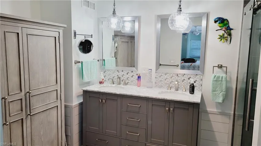 Master ensuite featuring double vanity, ensuite bath, a sink, and visible vents and tiled shower.
