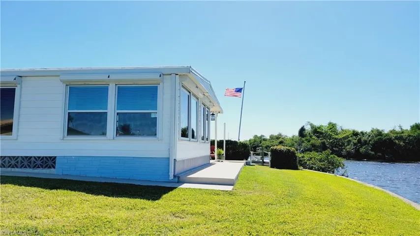 View of riverside of property featuring a water view and a lawn