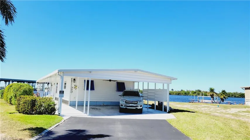 Manufactured / mobile home featuring a carport, driveway, and a front lawn