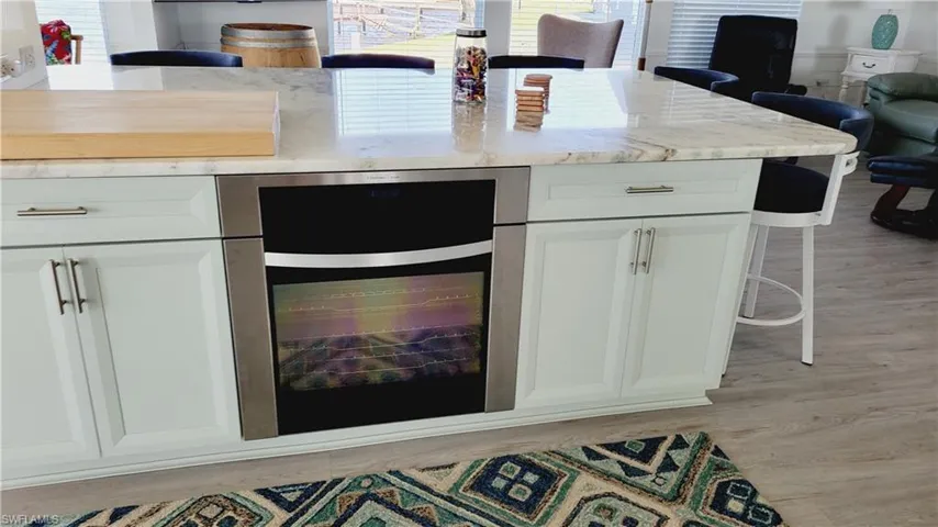 Large Marble Island with built in oven, cabinetry and seating.
