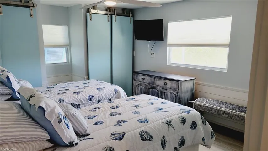 2nd Bedroom with a barn door, a ceiling fan, a wainscoted wall, vinyl finished floors.