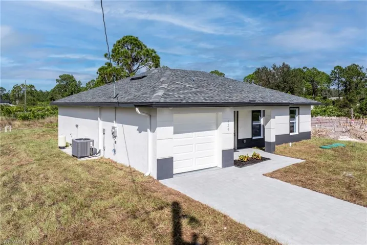 View of front of home featuring a garage, a front yard, and central air condition unit