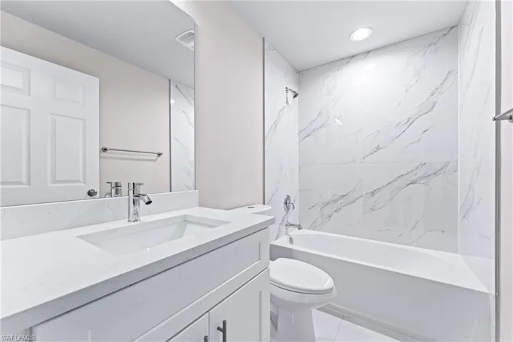 Full bathroom featuring tiled shower / bath, vanity, toilet, and tile patterned floors