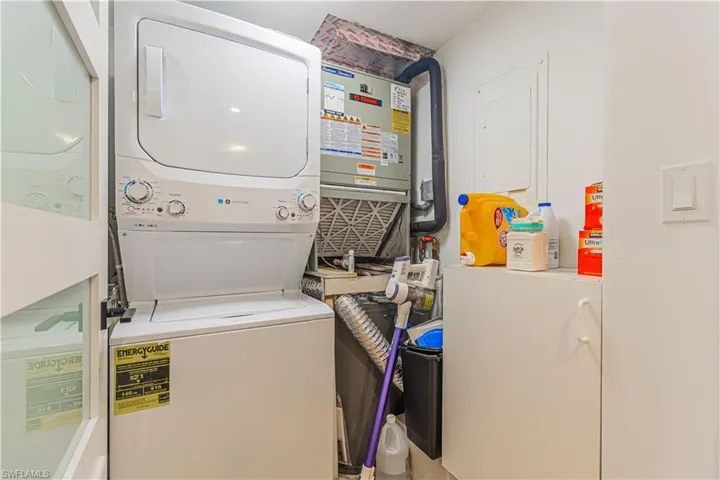 Dedicated laundry area featuring a stacked washer and dryer unit, and a built-in utility cabinet