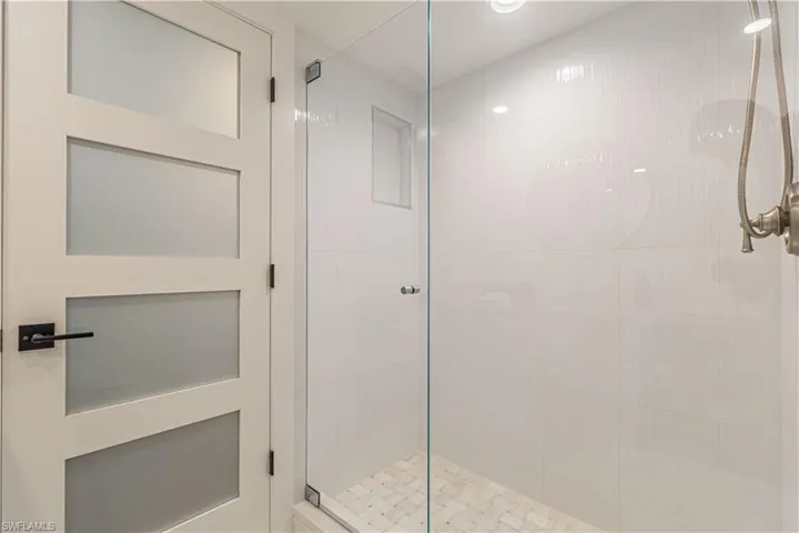 Guest Bathroom Walk-in shower featuring a frameless glass enclosure, white subway tile walls, a tiled shower pan, and brushed nickel shower fixtures
