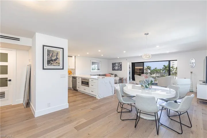 Open-concept living space featuring wood-finish flooring, recessed lighting, and a kitchen island with a waterfall-edge countertop