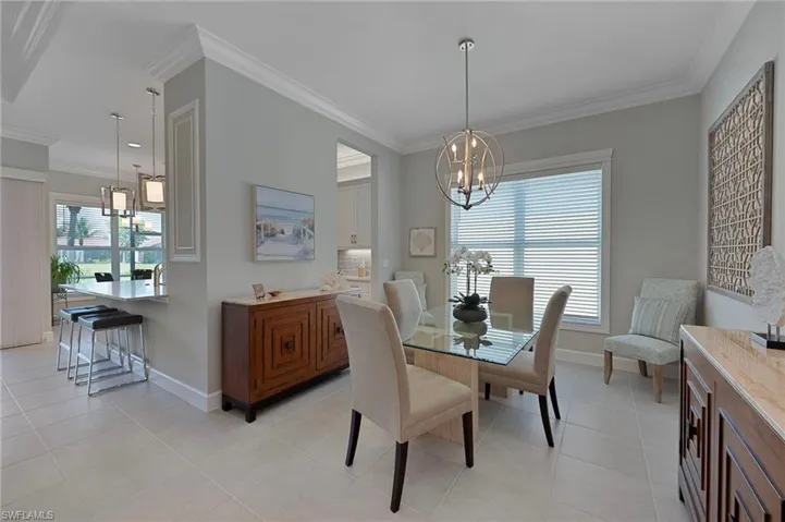 Dining room featuring a chandelier, custom crown moldings, porcelain tile