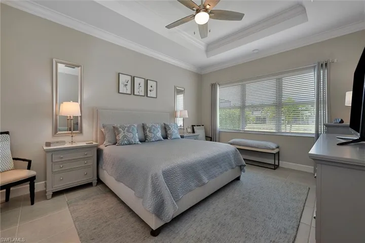 Spacious Master bedroom with  tray ceiling, light tile  flooring, custom moldings,