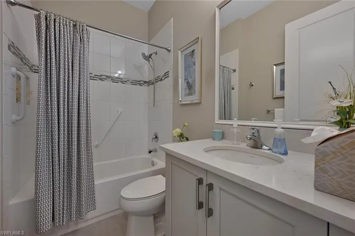 Full bathroom featuring vanity, shower / tub combo, and deco tile details