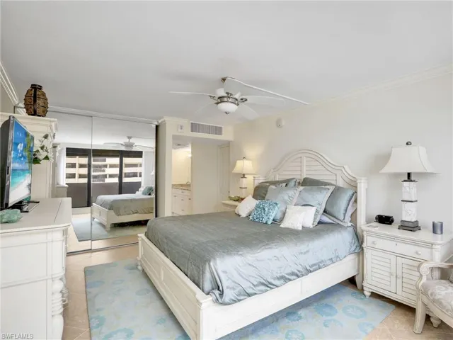 Bedroom with crown molding, light tile patterned floors, a closet, and a ceiling fan