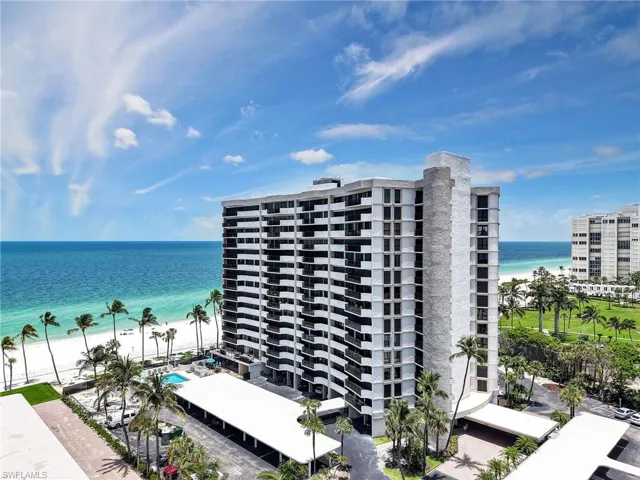 View of apartment building / complex featuring view of water and beach