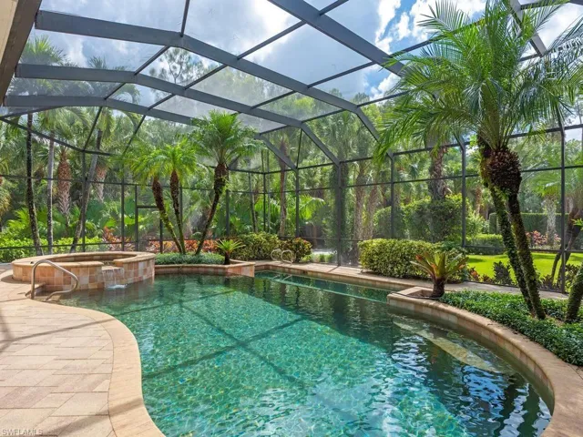 Screened lanai featuring a curved swimming pool, integrated spa with waterfall