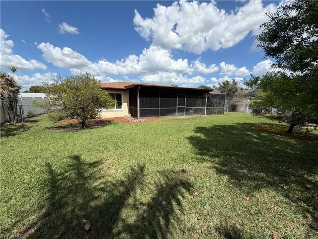 Rear view of house with a fenced backyard and a sunroom