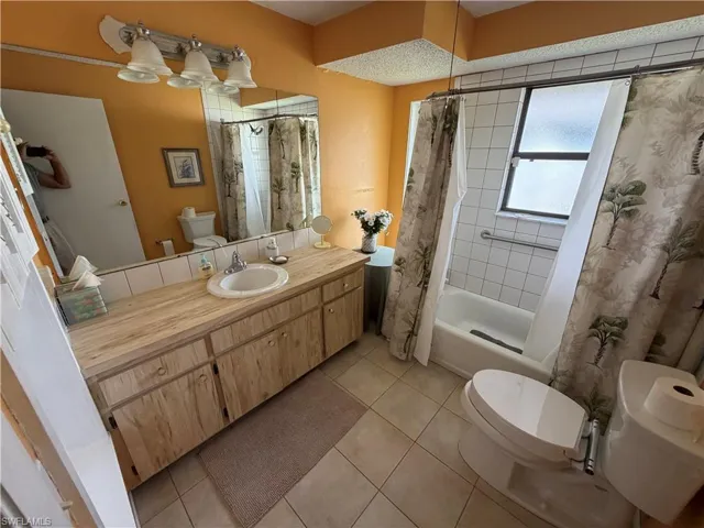 Full bath with vanity, light tile patterned flooring, and shower / bath combo