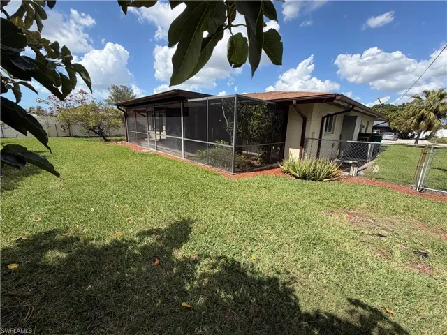 View of yard with a sunroom and a gate