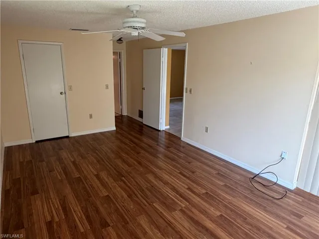 Unfurnished bedroom with a textured ceiling, a ceiling fan, and dark wood-style floors
