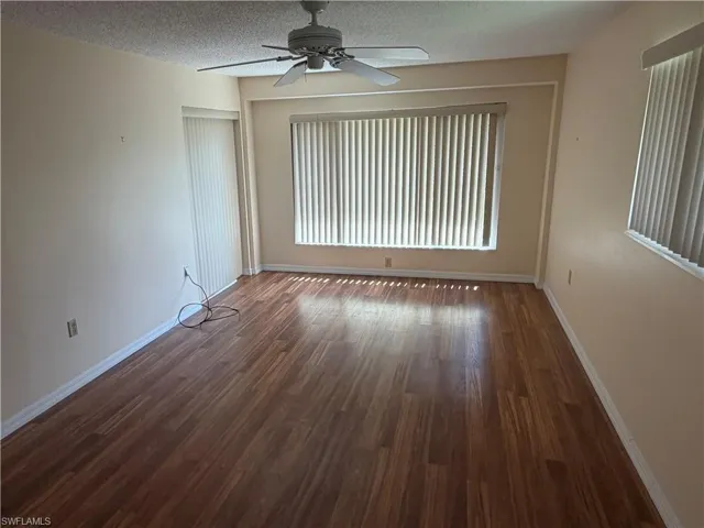 Unfurnished room with ceiling fan, a textured ceiling, and dark wood finished floors
