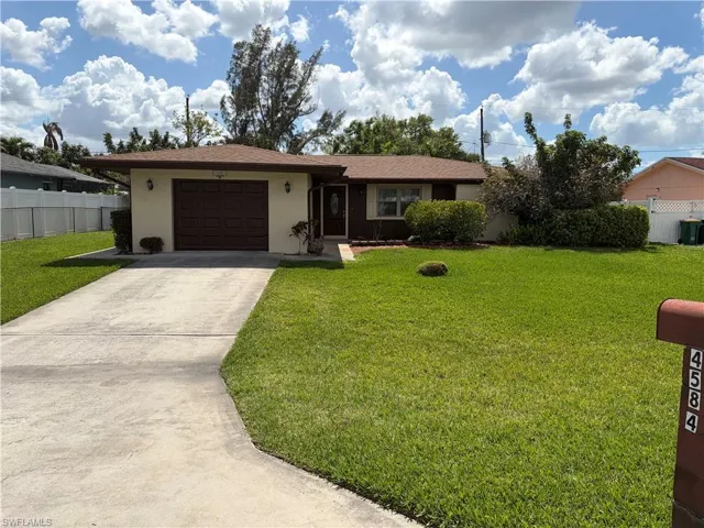 Ranch-style house with concrete driveway, an attached garage, and stucco siding